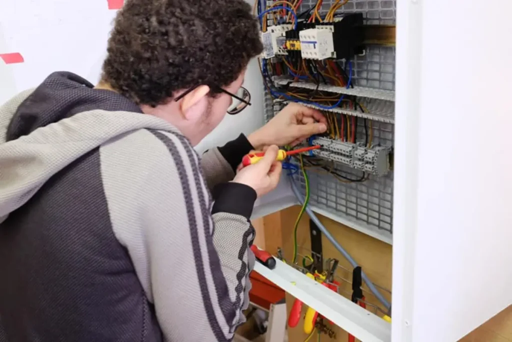 une photo qui montre un jeune élève - en formation chez CEFA de Bruxelles- en atelier installations électrique