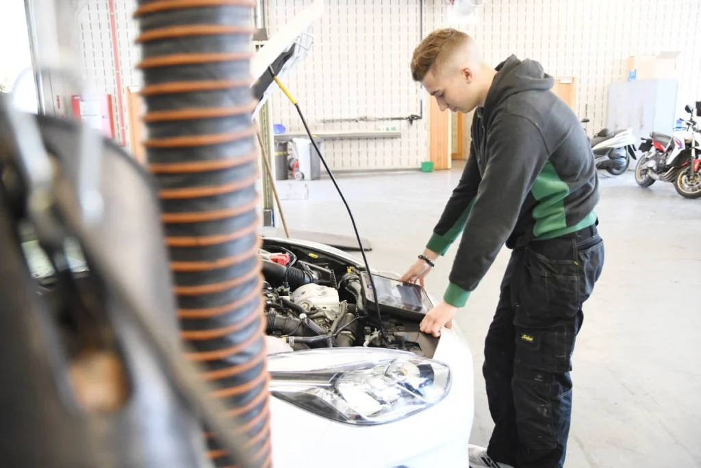 une photo qui montre un jeune élève mécanique - en formation chez CEFA de Bruxelles- en atelier maintenance auto